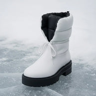 White winter boot with black sole and padded lining on icy surface, insulated snow footwear