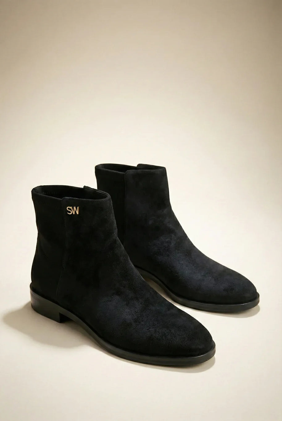 Pair of black suede ankle boots with low heels and gold SW logo on plain background