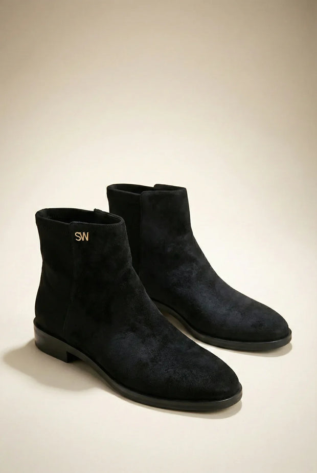 Pair of black suede ankle boots with low heels and gold SW logo on plain background