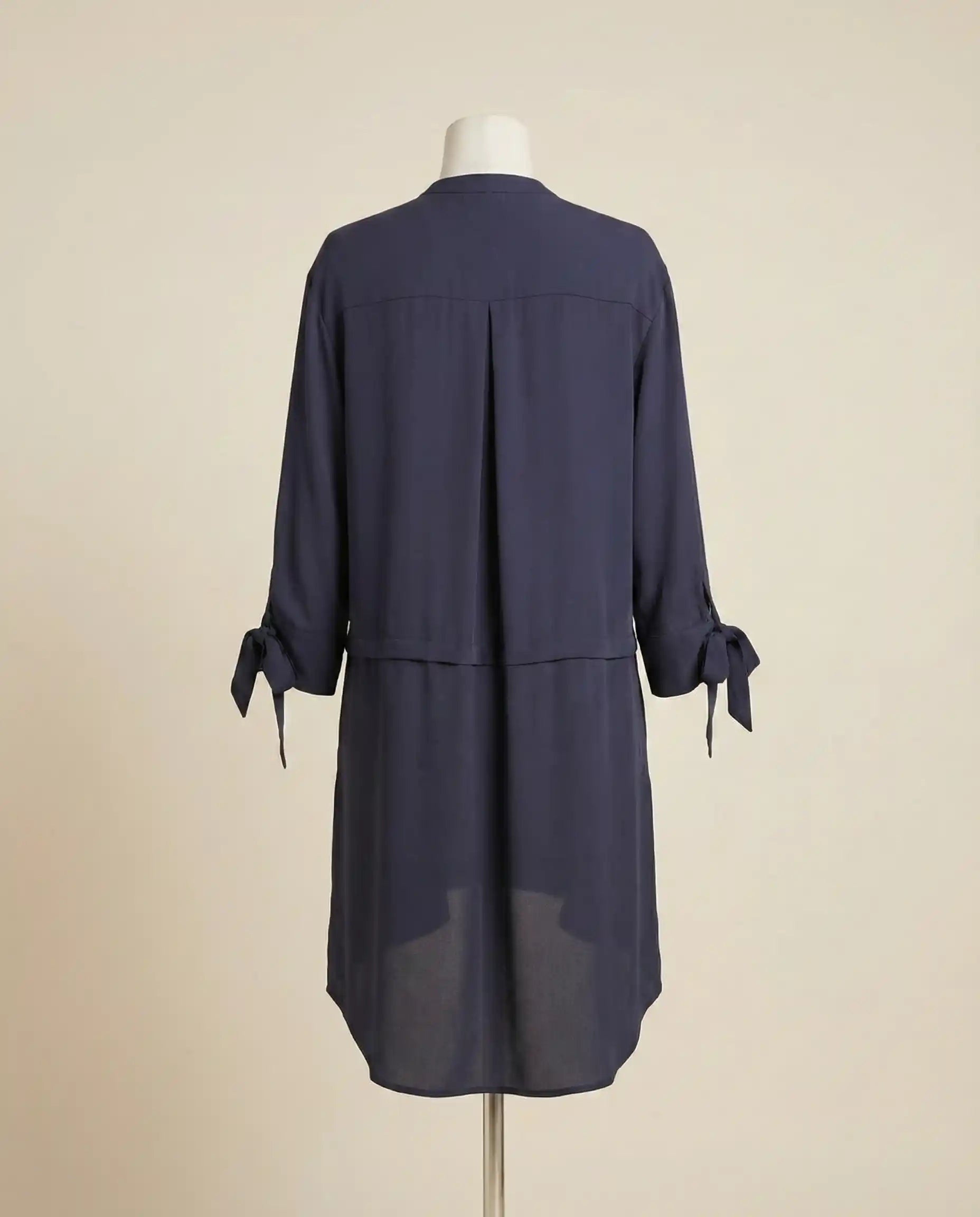 Back view of navy blue long-sleeve tunic dress with tie cuffs on mannequin