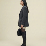 Woman in a gray blazer, sweater dress, black over-the-knee boots, holding a tote bag