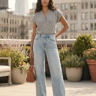 Woman wearing striped short sleeve blouse and high-waisted light wash jeans holding brown tote