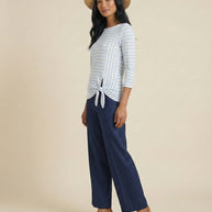 Woman in straw hat, blue striped tie-front top, wide-leg navy pants, wedge sandals