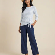 Woman in straw hat wearing striped tie-front top, navy wide-leg pants, and wedge sandals