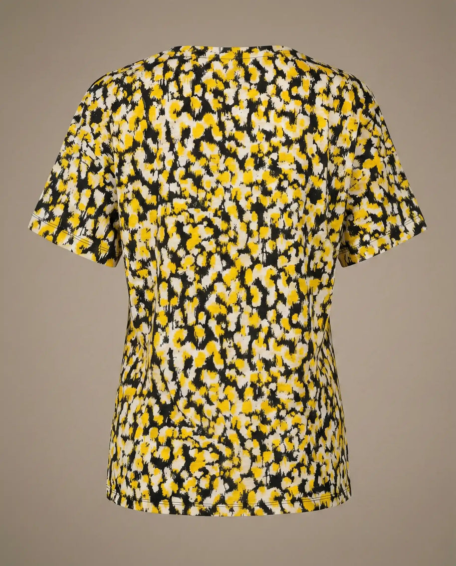 Back view of a short sleeve shirt with yellow, black, and white abstract floral pattern