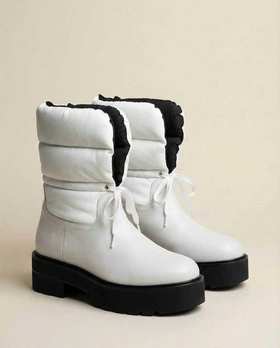 White winter boots with chunky black soles and quilted uppers, lace-up design, side view