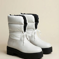 White winter boots with chunky black soles and quilted uppers, lace-up design, side view