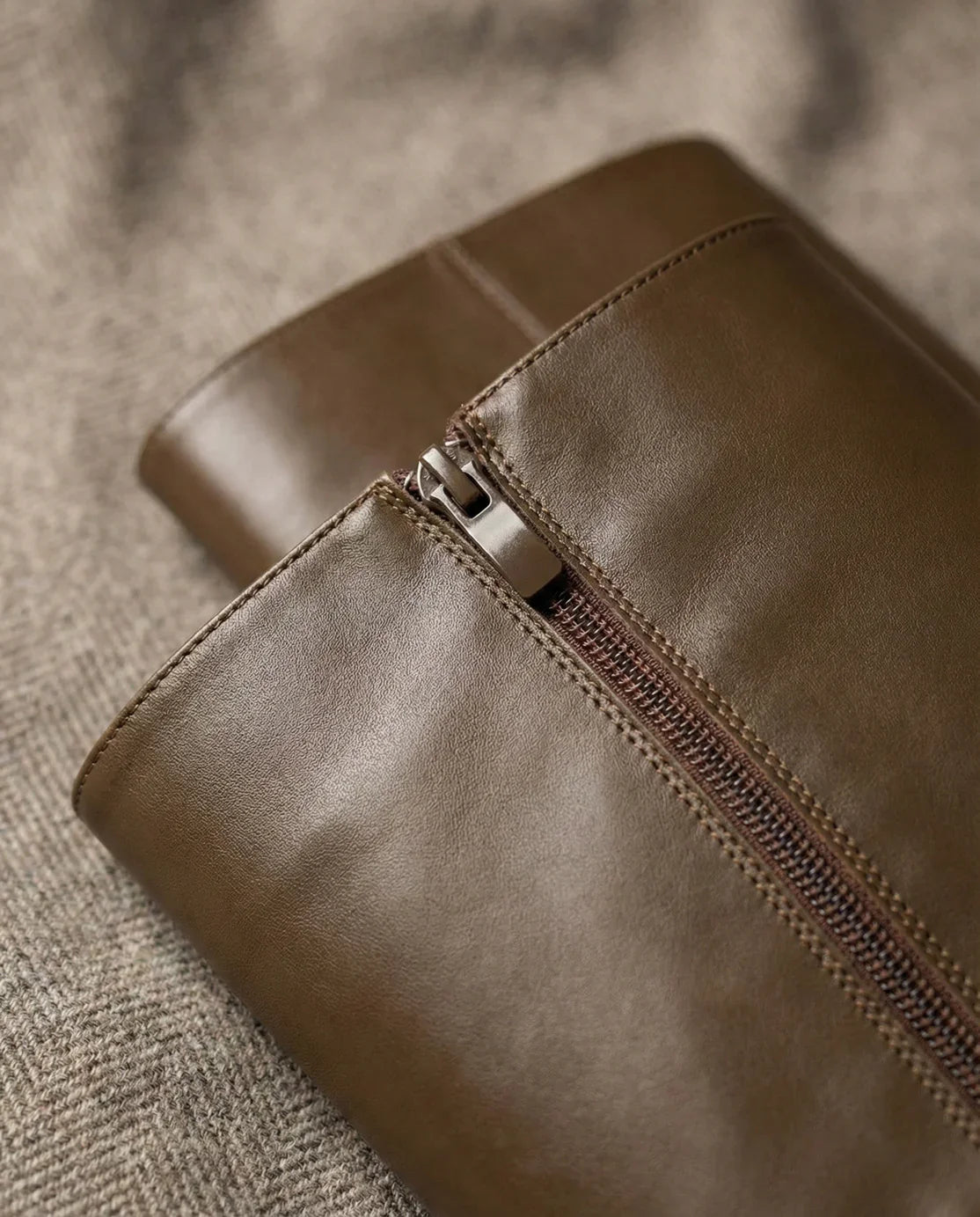 Close-up of brown leather bag with zipper on textured fabric background