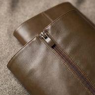 Close-up of brown leather bag with zipper on textured fabric background