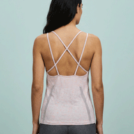 Woman wearing a light pink strappy back athletic tank top and gray leggings