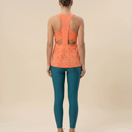 Woman wearing orange patterned racerback tank top and teal leggings, gym outfit