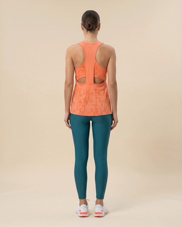 Woman wearing orange patterned racerback tank top and teal leggings, gym outfit