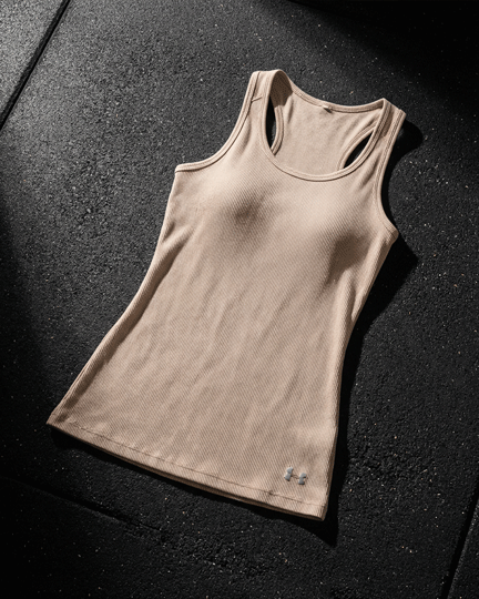 Beige athletic tank top with racerback design on textured black surface