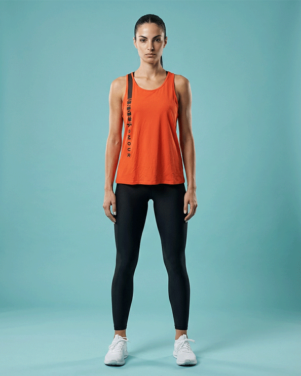 Woman wearing red Under Armour sleeveless workout top and black leggings, standing front view