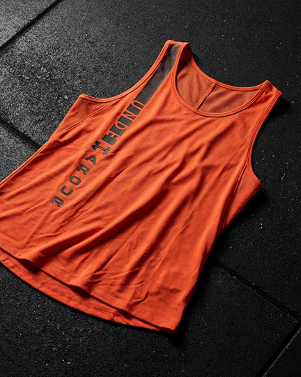 Red sleeveless Under Armour athletic shirt with black logo on gym floor