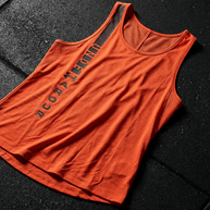 Red sleeveless Under Armour athletic shirt with black logo on gym floor