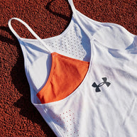 White athletic tank top with orange asymmetric design and perforated details on textured ground