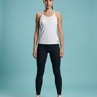 Woman modeling white athletic tank top, black leggings, and white-orange running shoes