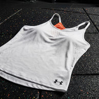 White athletic tank top with orange asymmetric accent and perforated sides on gym floor