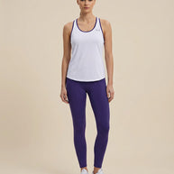 Woman wearing light blue athletic tank top with purple trim and purple leggings, standing indoors