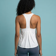 Woman wearing white racerback tank top and gray leggings, viewed from the back