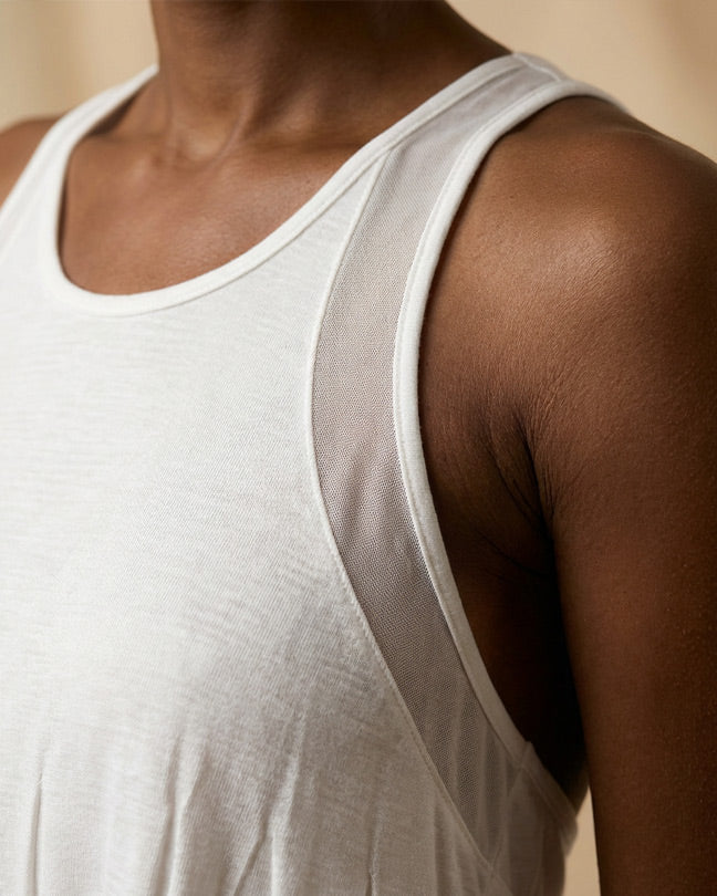 Closeup of a person wearing a white sleeveless athletic shirt with mesh underarm panel