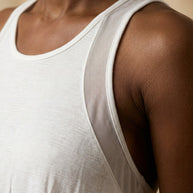 Closeup of a person wearing a white sleeveless athletic shirt with mesh underarm panel