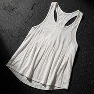 White racerback tank top with lightweight fabric on a textured black gym floor