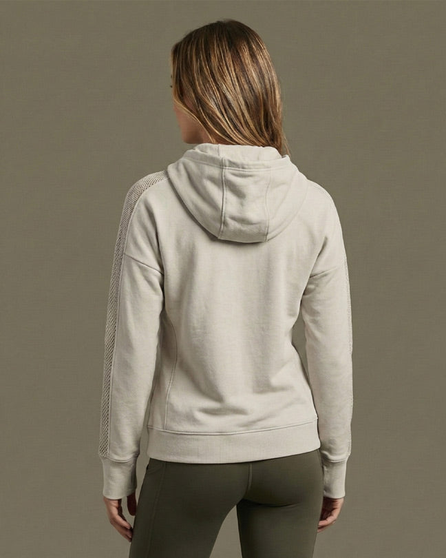 Back view of woman wearing a light beige hooded sweatshirt with textured sleeves.