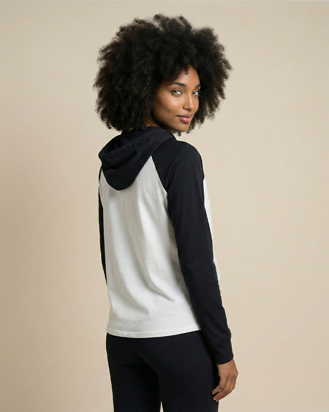 Woman wearing a black and white long sleeve hoodie with black pants, facing away