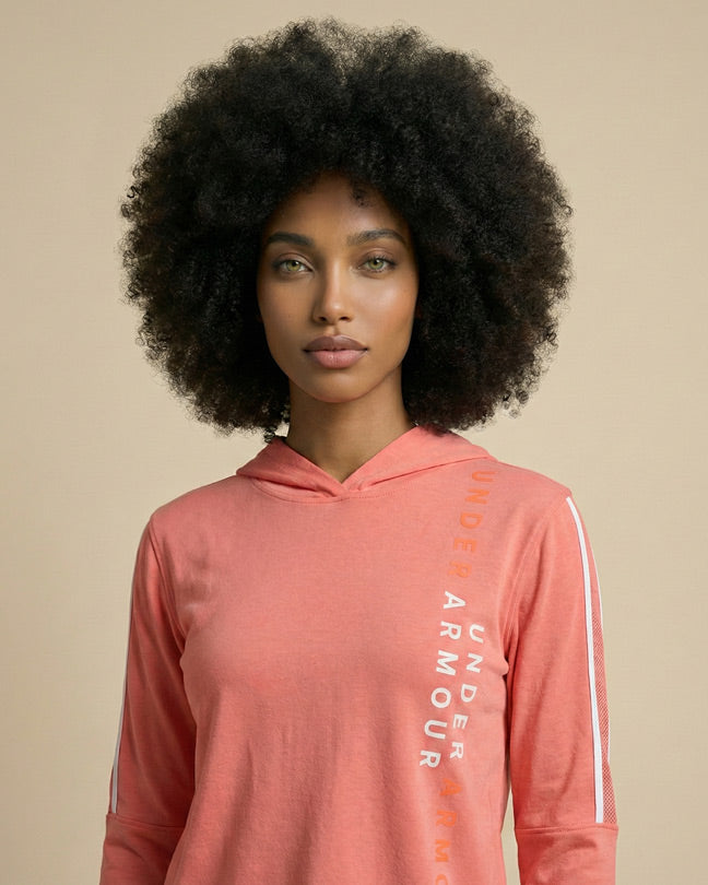 Woman wearing coral Under Armour hooded sweatshirt with white logo text, neutral background