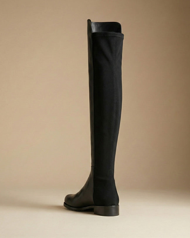 Black knee-high leather boot with flat heel on neutral background