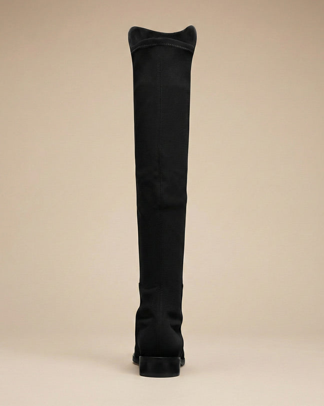 Black over-the-knee boot with low heel, rear view on neutral background