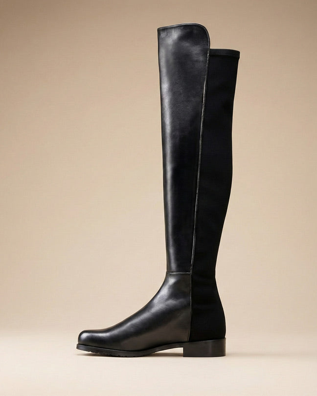 Black knee-high leather boot with low block heel on a neutral background