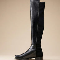 Black knee-high leather boot with low block heel on a neutral background