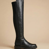 Black knee-high leather boot with a chunky sole on a neutral background