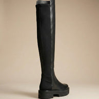 Black over-the-knee boot with chunky sole on neutral background