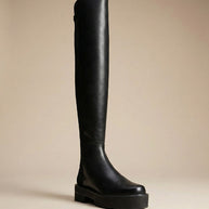 Black over-the-knee platform boot with thick sole on neutral background