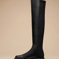 Black over-the-knee riding boot with chunky sole on neutral background