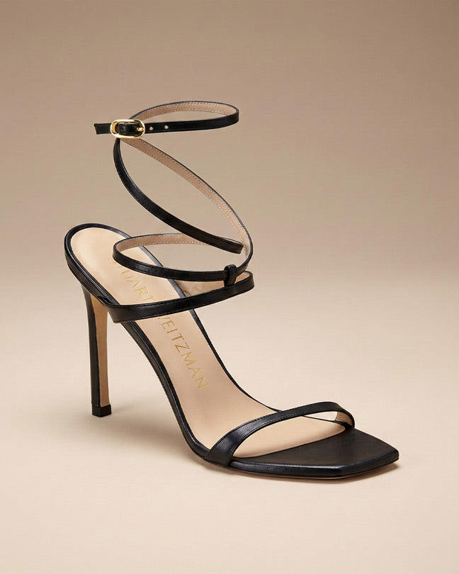 Black strappy high heel sandal with ankle wrap and square toe on beige background