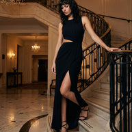 Elegant woman in black evening gown with thigh-high slit, posing on grand marble staircase