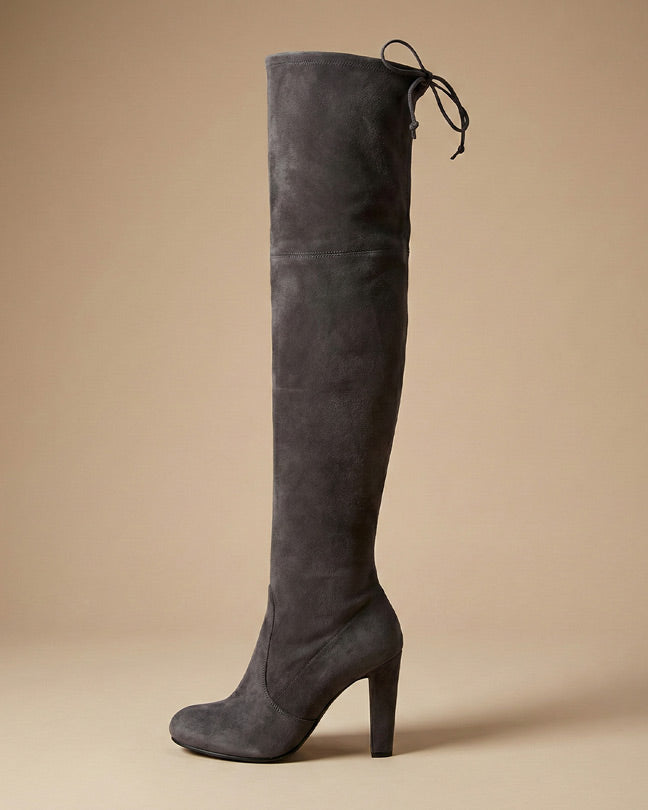 Gray suede over-the-knee heeled boot with tie-back detail on neutral background