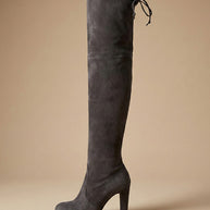 Gray suede over-the-knee heeled boot with tie-back detail on neutral background