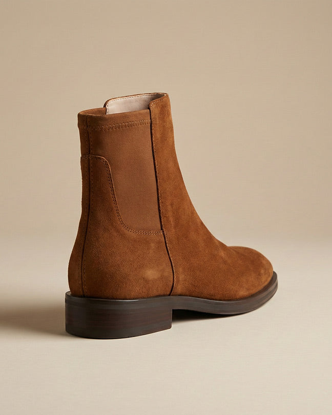 Brown suede Chelsea boot with elastic side panel on neutral background