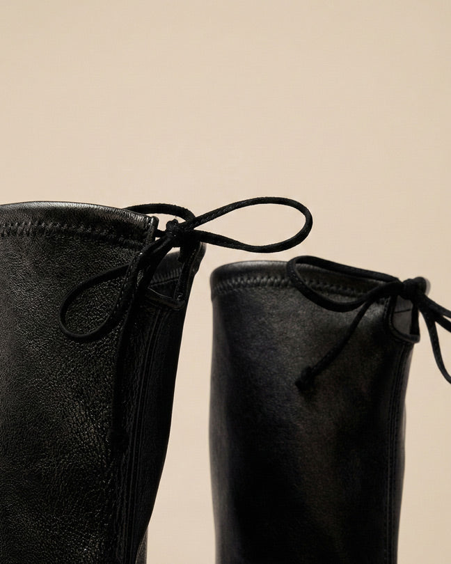 Close-up of black leather boots with front laces and textured finish