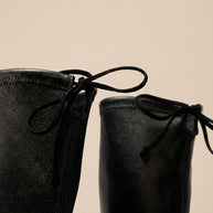 Close-up of black leather boots with front laces and textured finish