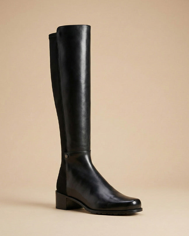 Black knee-high leather boot with low block heel on a neutral background
