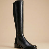 Black knee-high leather boot with low block heel on a neutral background