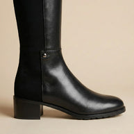 Black knee-high leather boot with block heel on beige background