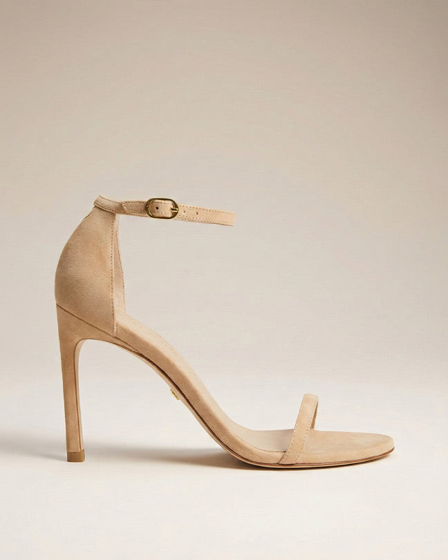 Beige suede high heel sandal with ankle strap and open toe on a neutral background